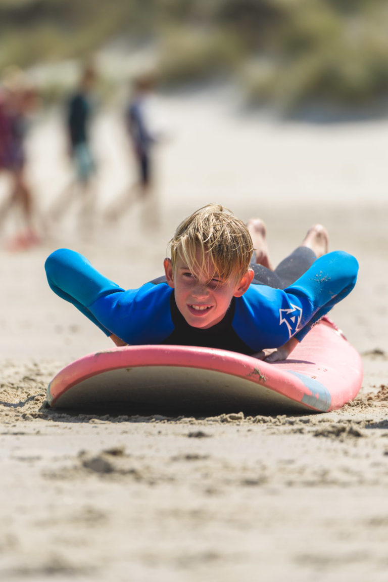 jongen tijdens surfles op strand zomerkamp vlieland